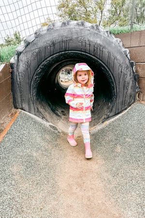 toddler girl coming through tunnel on play area at underwood farms